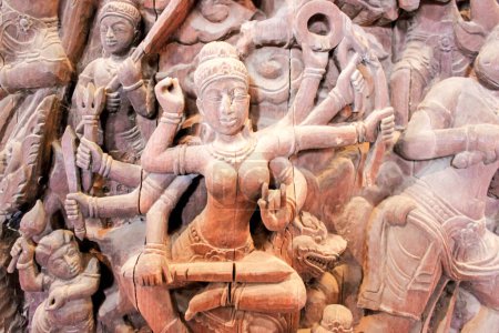 Schöne, detaillierte Steinschnitzerei einer hinduistischen Göttin mit mehreren Armen, die in einem antiken Tempel ausgestellt wird.