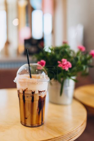 Foto de Café helado en taza de plástico servido con cobertura de crema batida y jarabe dulce. Refresco de bebidas favorito - Imagen libre de derechos