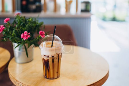 Foto de Café helado en taza de plástico servido con cobertura de crema batida y jarabe dulce. Refresco de bebidas favorito - Imagen libre de derechos