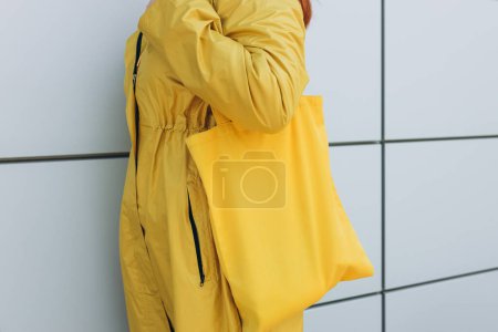 Foto de Modelo mantenga en blanco bolsa de tela amarilla para salvar el medio ambiente en la moda callejera. Eco naturaleza estilo amistoso. - Imagen libre de derechos