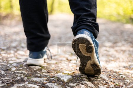 Téléchargez les photos : Gros plan des chaussures de randonneurs masculins. Pieds d'un athlète courant sur un sentier du parc pour s'entraîner à la forme physique, bannière mode de vie sain - en image libre de droit