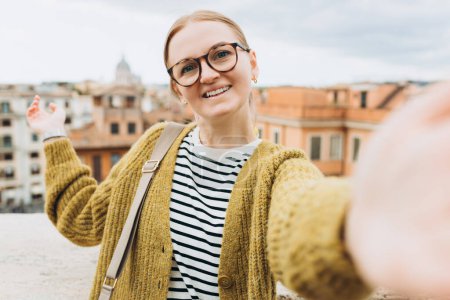 Téléchargez les photos : Femme jouissant d'un beau paysage urbain matinal de Rome, prendre des photos selfie, tout en étant assis sur le dessus des célèbres marches espagnoles. - en image libre de droit