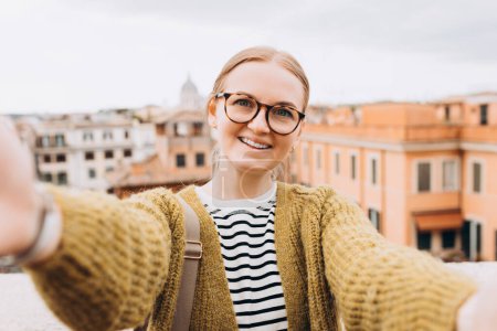 Téléchargez les photos : Femme jouissant d'un beau paysage urbain matinal de Rome, prendre des photos selfie, tout en étant assis sur le dessus des célèbres marches espagnoles. - en image libre de droit
