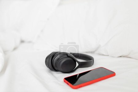 Téléchargez les photos : Casques et smartphone sur un lit. Concept de moment relaxant. - en image libre de droit