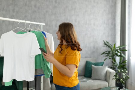 Frau sucht Kleidung aus, die sie für einen Charity-Laden spenden kann. Wiederverwendung, Second-Hand-Konzept. Bewusster Verbraucher, nachhaltiger Lebensstil.