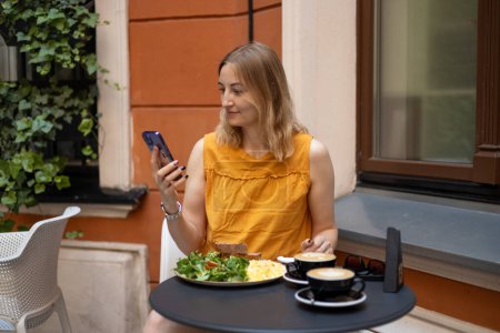 Portrait of beautiful 30s girl drinking in a cafe drinking coffee, happy emotions. Young happy woman smiling and using smart phone in a cafe. Phone Communication.