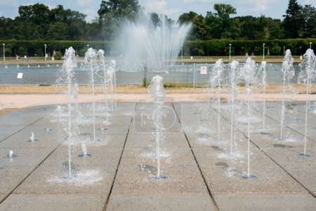 Wassertröpfchen verteilen sich aus der Fontäne in der Luft. Spritzwasser aus einem Springbrunnen im Park