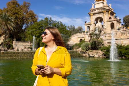 Junge Touristin mit Telefon besucht den Ciutadella Park in Barcelona. Konzept für Reisen, Tourismus und Urlaub in der Stadt. Technologiekonzept nutzen