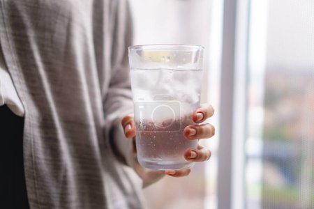 woman holding a glass of cold water with ice cubes