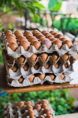 close up stack of eggs in a paper tray on a wooden cabinet 