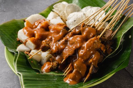 sate padang, indonesian cuisine padang beef, intestine satay with spicy peanut sauce and rice cake