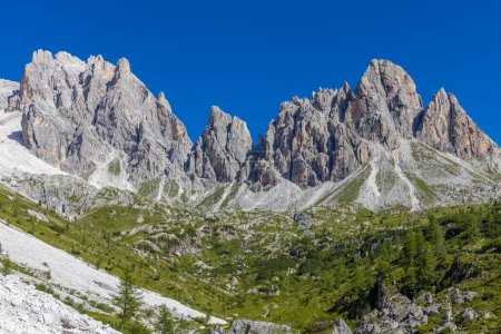 Dolomiti Alps beautiful mountain landscape. Rocky tower alpine summits in the Dolomites. Summer mountain scenic view on the hiking trekking path in the green mountain valley and blue sky with clouds