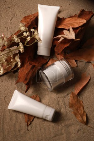 Organic Skincare Products on Sand with Autumn Leaves and Rustic Wood