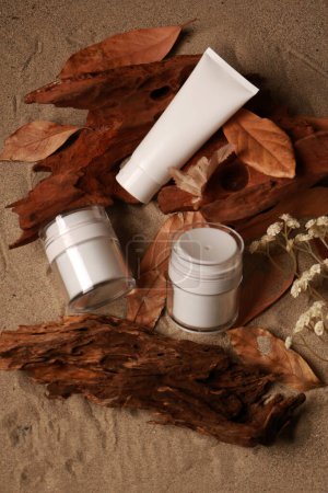 Produits naturels pour la peau sur fond sablonneux avec feuilles d'automne et bois