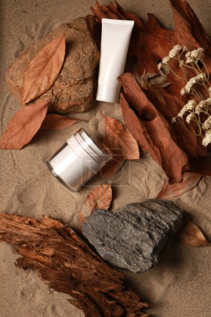 Produits naturels pour la peau sur fond rustique sablonneux avec feuilles d'automne et bois flotté