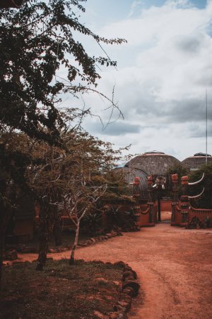 This evocative photograph captures the entrance to a traditional African village in South Africa, with intricate decorations and lush surroundings. Ideal for cultural and travel enthusiasts, highlighting local heritage.
