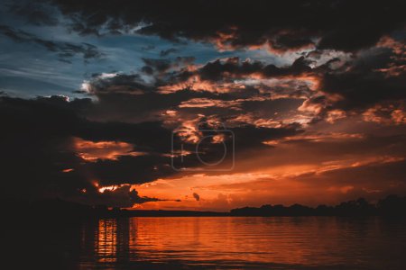 A mesmerizing image capturing fiery dusk over the Zambezi River with intense hues of orange and red reflecting on the water and dramatic clouds creating a powerful and evocative scene perfect for impactful projects.