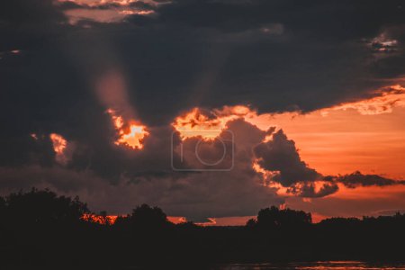 A captivating image of blazing sunset clouds over the Zambezi River with vibrant hues of red and orange illuminating the sky creating a powerful and dramatic scene ideal for striking visual projects.