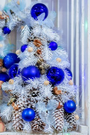 Photo for Small white Christmas tree decorated with blue balls and cones. - Royalty Free Image