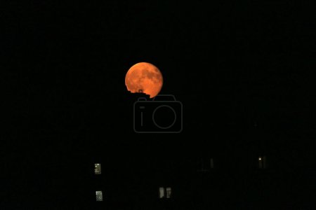 Téléchargez les photos : La pleine lune s'est levée sur des bâtiments de plusieurs étages dans la ville - en image libre de droit