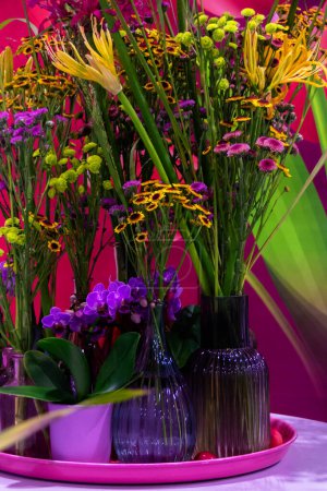 Photo for Bouquets of wildflowers in multi-colored decorative glass bottles - Royalty Free Image