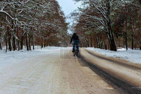 A cyclist rides on a slippery snowy road in winter