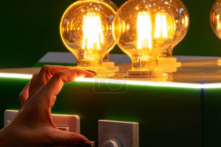 Ein Mann schaltet runde Energiesparlampen in einer Glühbirne mit warmem Licht ein