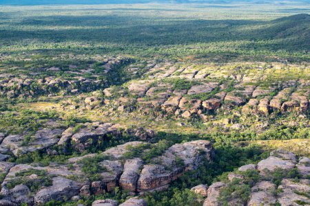 escarpado paisaje de Outback cerca de Cobbold Gorge en FNQ, Australia, con formaciones rocosas antiguas, vegetación escasa y un vasto paisaje indómito. Esta remota área ofrece un vistazo a la belleza cruda y el entorno hostil del Outback australiano