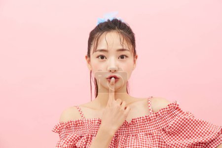 Casual portrait of a young Asian woman photographed against a pink background