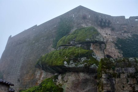 Walls between rocks of the Sortelha fortress on a foggy day and view from below