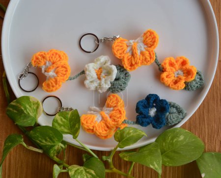 Handgefertigte Schönheit: Häkelnde Schmetterling-Schlüsselanhänger mit Blumen auf natürlichem Hintergrund