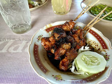 Satay indonesio o Sate Kambing, satay de carne de cabra servido con pepino, rebanada de col y salsa de soja en un plato