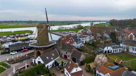 Beautiful view from above, from drone to orange, tiled roofs of houses. Top view of the Dutch city of Wijk bij Duurstede. The streets and roof of the church. Central Square of the city. Beautiful windmills.