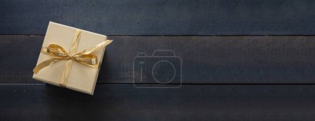 Foto de Caja de regalo con cinta dorada sobre fondo de madera azul, espacio para copiar. Regalos de Navidad - Imagen libre de derechos