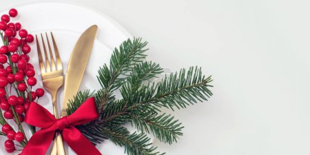 Photo for Christmas holiday celebration dinner. New Year table setting isolated on white. Golden cutlery, Xmas decoration and red ribbon top view. - Royalty Free Image