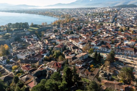 Photo for Greece, Ioannina Pamvotida Lake, Epirus. Aerial drone view of Giannena city red tile roof buildings, blue sky background. - Royalty Free Image