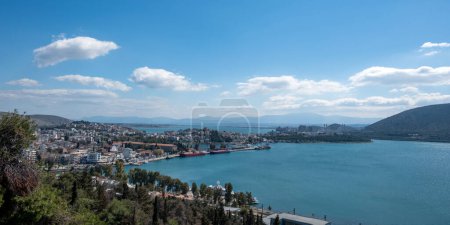 Greece, destination city of Chalkida at Evia. Close up view of Halkida port from castle, moored ship, building, Euripus Strait, cloudy sky background.