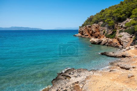 Playa Dragonera, Isla Agistri en el Golfo Sarónico, Grecia. Paisaje rocoso cubierto de pino, mar cristalino, cielo azul, destino de verano.