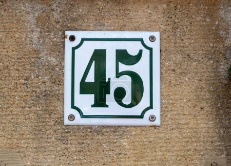 Photo for White metallic sign with black number digit 45 on rough brown plastered cement wall background. Signage bolted on stonewall. - Royalty Free Image
