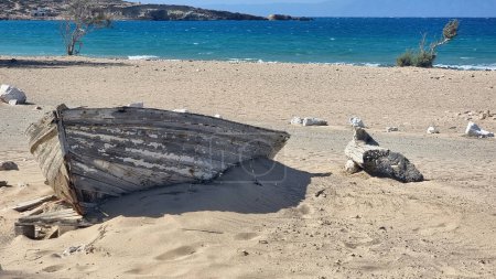 Isla Gavdos, Sarakiniko playa nudista de arena, Creta Grecia. Barco destruido por el viento y la sal en la costa. Mar ondulado, cielo azul, día soleado.