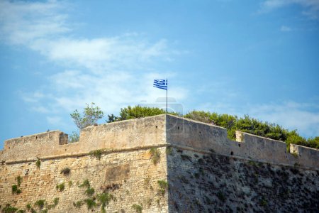 Koules Venezianische Festung im alten Hafen von Heraklion, Insel Kreta Destination Griechenland. Griechen schwenken Flagge auf Steinmauer berühmtes Monument, blauer Himmel Hintergrund.