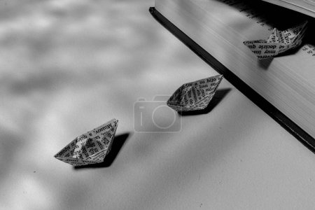 three paper boats coming out of a book