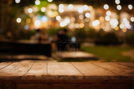 Foto de Mesa de madera vacía y desenfoque de restaurante cafetería en fondo oscuro noche - Imagen libre de derechos