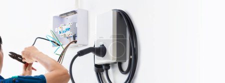 Photo for Certified male Electrician Installing Home EV Charger - Royalty Free Image
