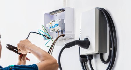 Téléchargez les photos : Électricien masculin certifié installant le chargeur d'EV à la maison - en image libre de droit