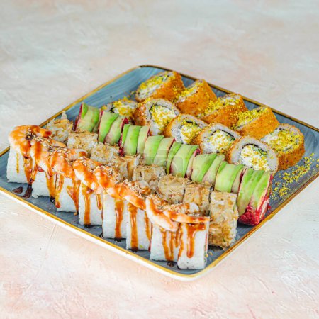 A platter filled with an assortment of sushi rolls, expertly crafted and topped with a drizzle of flavorful sauce.