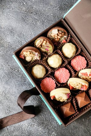 Une boîte remplie de différents types de chocolats placés sur une table.