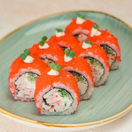 A plate of sushi topped with red sauce and garnished with fresh ingredients.