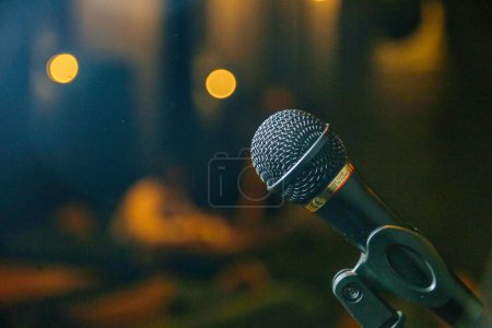 Foto de Un micrófono de alta calidad se coloca de forma segura en un soporte duradero, listo para amplificar las voces o las actuaciones musicales durante los eventos teatrales. - Imagen libre de derechos
