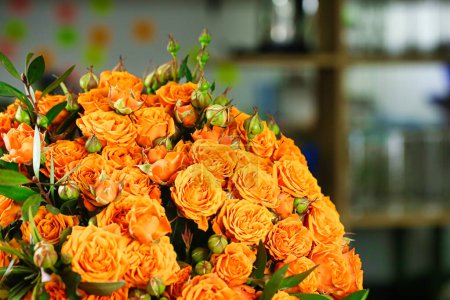 A beautiful arrangement of orange roses on a table, surrounded by ample copy space.